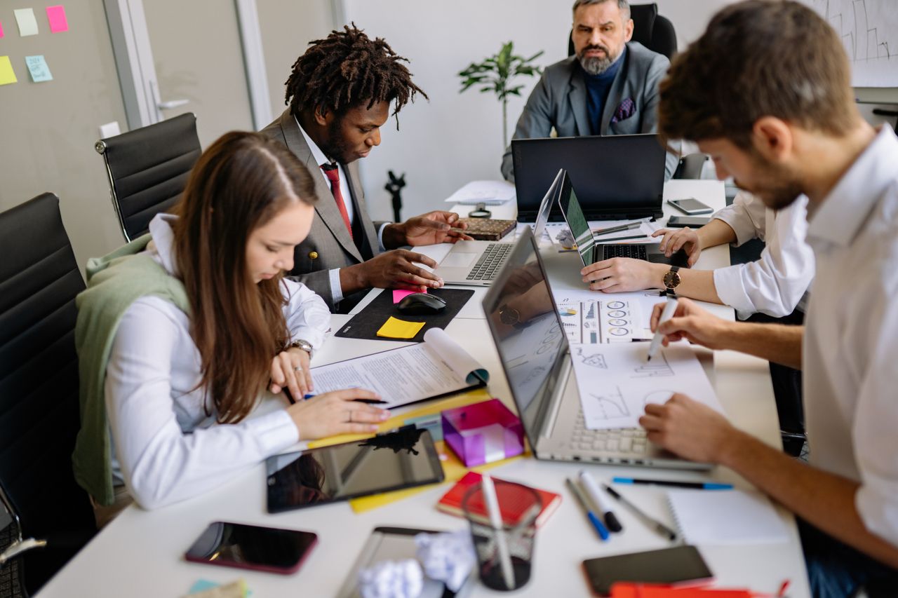 The Art of Drawing Readers In: Your attractive post title goes here Team of professionals collaborating around a table in a modern office, focusing on projects and discussions.